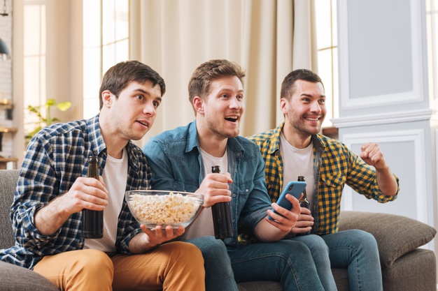 young-men-sitting-sofa-watching-sport-event-television-home_23-2148160261